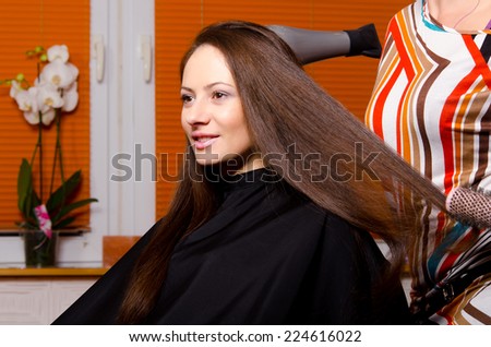 Hairdresser making hair of beautiful happy girl in hair salon.