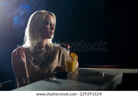 Beautiful elegant lady sitting alone in the night club and smoking cigarette.
