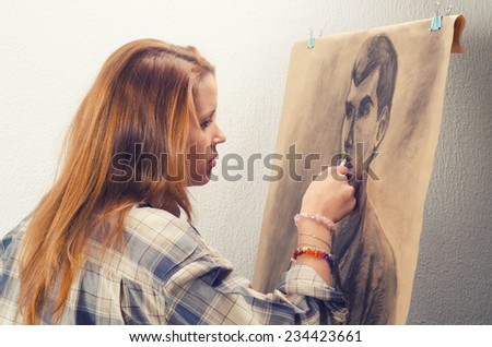 Young female artist drawing man portrait in her art studio.