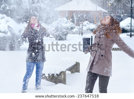 Two teenage girls having fun in the snow on beautiful winter day.
