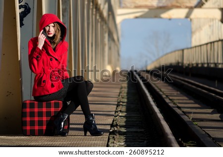 Beautiful fashionable girl waiting for the train on sunny windy day.