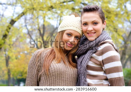 Two beautiful girlfriends having fun in the park on colorful autumn day.