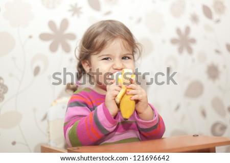 little girl eating banana sitting in high chair