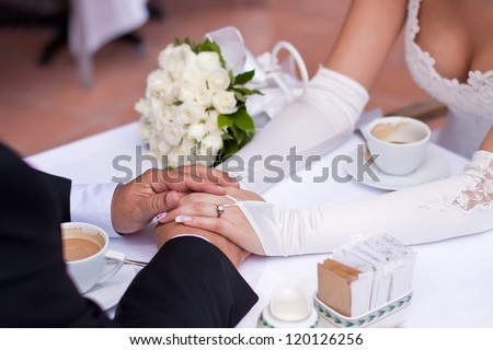 bride\'s and groom\'s hands holding each other on a table