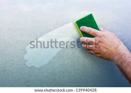 hand Cleaning car using a yellow cleaning sponge