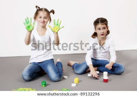 Portrait of cute twin girls with finger paintings having fun