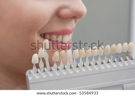 Choice of color of a dental artificial limb. The woman on reception at the dentist. Close-up