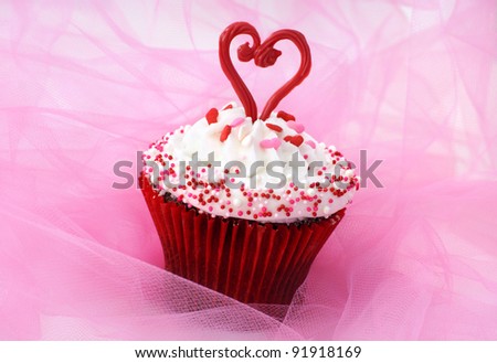 Cupcake decorated with sprinkles and a red chocolate heart
