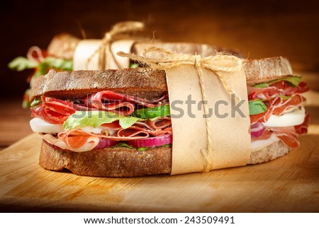 Sandwich with bacon and fresh vegetables on vintage wooden cutting board. Close-up.