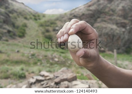 hand holding a bird egg in the mountains