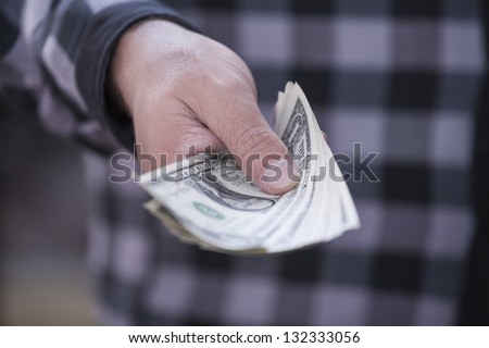 hand in a plaid shirt keeps money