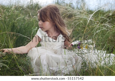 Fairy-tale beautiful little girl on a lawn with the field flowers