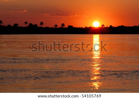 An orange sunset over the Zambezi river in Zambia.  The sun and the reflection create a cool letter \'i\'.  The water at the bottom of the frame can easily be cloned out to make the \'i\' more obvious.
