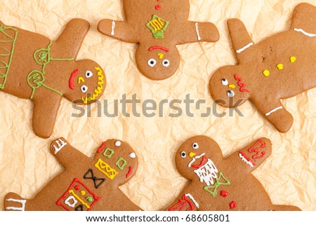 Some freshly baked home made gingerbread men arranged in a circle on some creased parchment paper (baking paper).