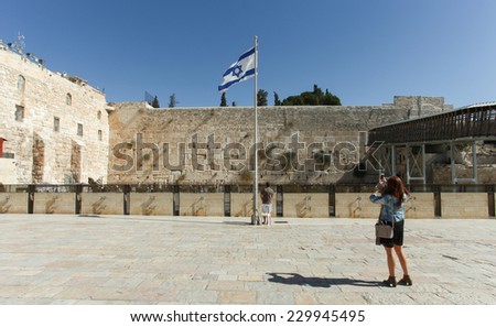 Jerusalem, Israel - November 9, 2014 : Tourist taking a photo at Jerusalem\'s wailing wall compound with blue sky, the Israeli flag and the wailing wall in the background