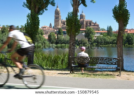 Elder man on bench during walk beside the river, Salamanca