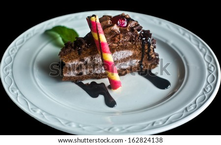 Piece of chocolate cake with biscuit rolls, mint and xyrup