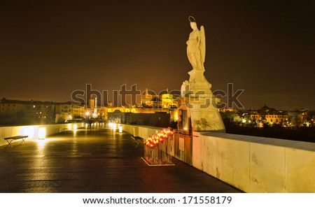 Night scene of Archangel Raphael statue on roman bridge at Cordoba, Spain