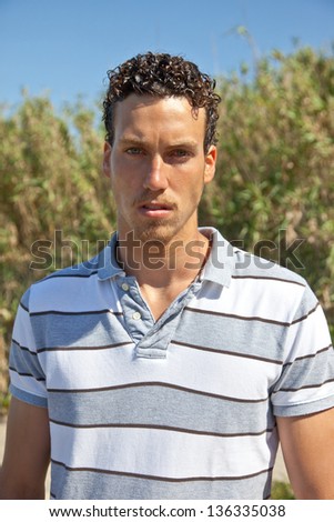 Handsome young man standing in front of a corn field looking worried.