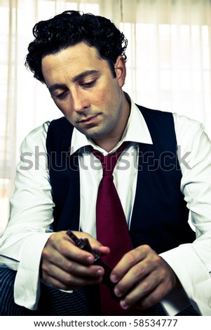 Retro - dressed up attractive man looking at a chess piece with worry