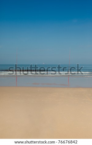 Two fishing rods on an empty tropical beach.