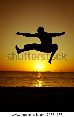 Silhouette of a man jumping at the beach during sunset