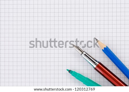 school supplies on checked paper notepad background