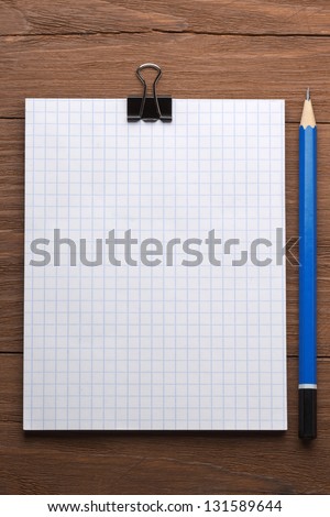 checked notepad and pencil on wood background