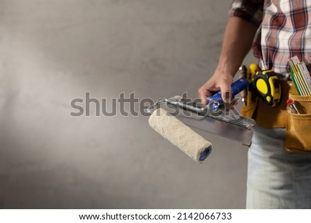 Construction worker man holding paint roller tool in house room renovation. Male hand and construction tools near concrete or plaster wall. Home renovation concept Foto stock © 