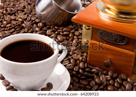 cup of coffee, pot and grinder on roasted beans