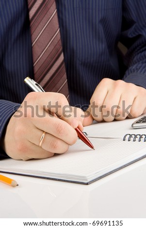 male hand writing by pen on checked notebook