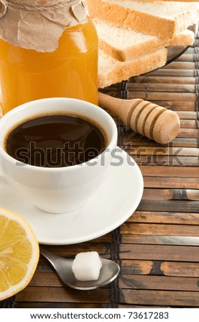 coffee, honey, lemon and bread on straw table