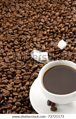 cup of coffee and spoon on roasted beans as background
