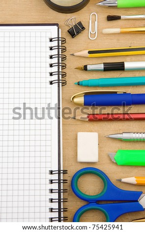 school accessories and checked notebook on wooden texture