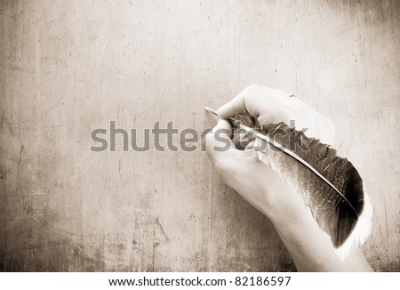 writing hand and pen feather on wood background