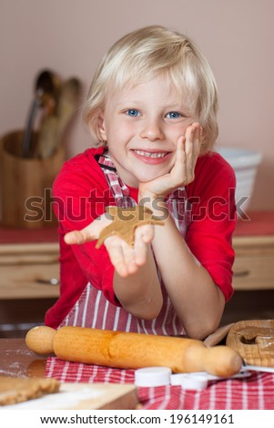 A cute young very proud boy is holding up a gingerbread star cookie he just baked