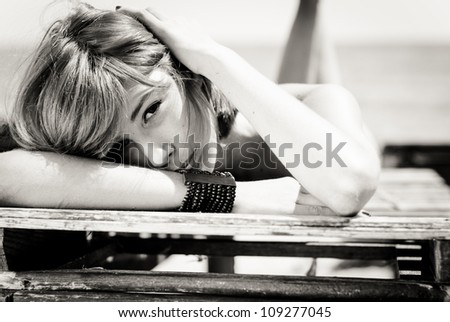 Young beautiful woman lying on wooden lounge head shot black and white