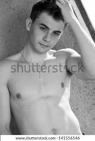 Happy young stylish man hands crossed on naked torso looking away black and white