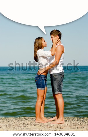 Young happy couple at sea coast sitting hugging dialog box above them