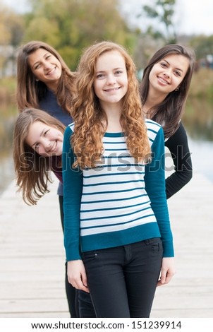 Four happy teenage girls friends outdoors happy smiling & having fun