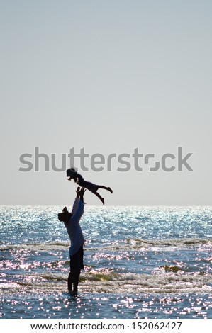 Happy father and little son or daughter on sandy beach having fun on sea holiday outdoors happy smiling