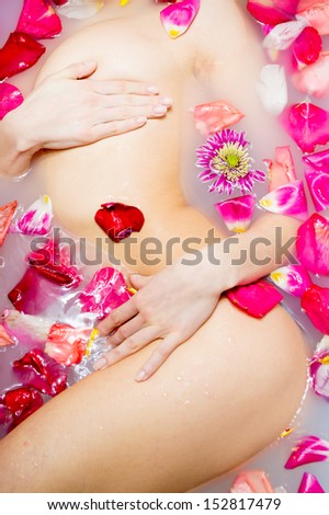 Sexy young female in bath with flowers petal.