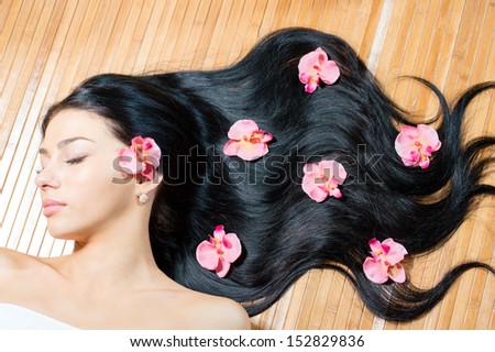 Portrait of a beautiful young woman face with perfect skin & lips, pink flowers in long hair