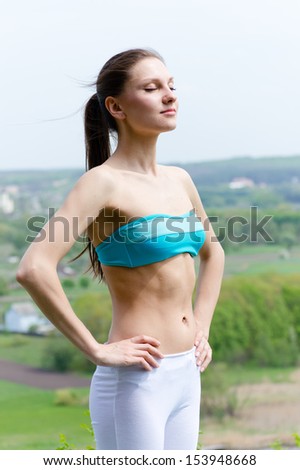 Beautiful young woman in sportswear standing outdoors on summer day outdoors background