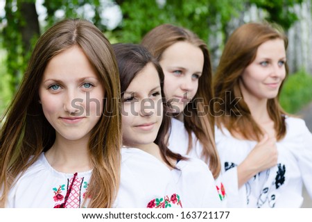 Four happy girls standing in line face to face on summer or spring day outdoors background