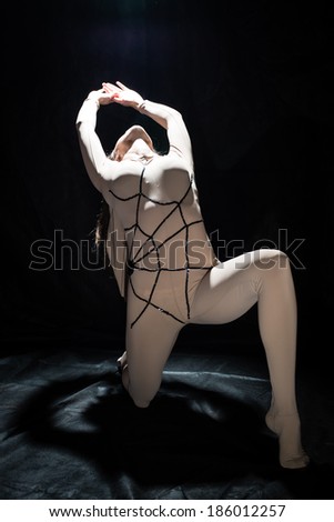 Spider girl: young attractive performer seductive woman with a wonderful body in a extraordinary spider bodysuit on black background