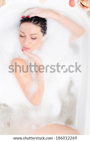 attractive beautiful sexual happy young woman lying in the bath with soap foam portrait