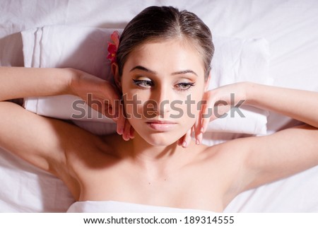 young beautiful woman with orchid  lying on her back and relaxing with bare shoulders looking dreamy closeup portrait picture