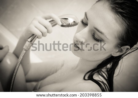 sensual water cleaning: pretty woman relaxing taking shower in bath eyes closed on copy space background closeup black and white portrait image