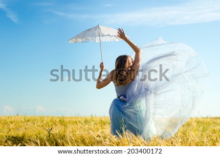 image of holding white lace umbrella sensual beautiful blond young woman wearing long blue ball dress and leaning up on summer outdoors wheat field and blue sky copy space background portrait